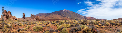 Panoramic view of unique Roque Cinchado unique rock formation with famous Pico del Teide mountain volcano summit in the background on a sunny day  Teide National Park  Tenerife  Canary Islands  Spain