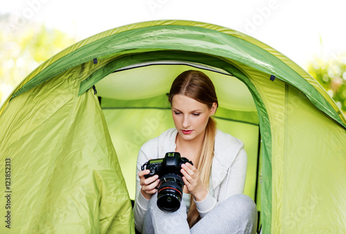 Young woman witho photo camera in a tent on the nature photo