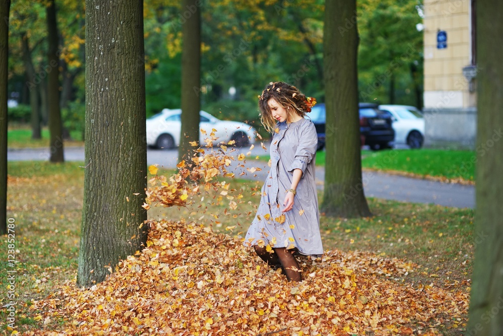 Beautiful smiling girl with dreadlocks in a lavender cloak having fun in the alley between the trees , jumping on pile of yellow leaves. Beautiful smiling girl with dreadlocks in a lavender cloak having fun in the alley between the trees , jumping on pile of yellow leaves.