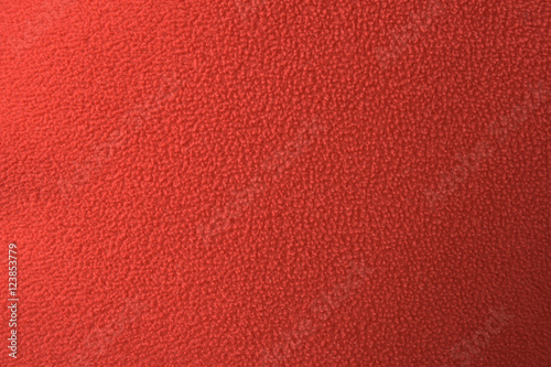 Close-up of red polar fleece fabric with pilling, material texture