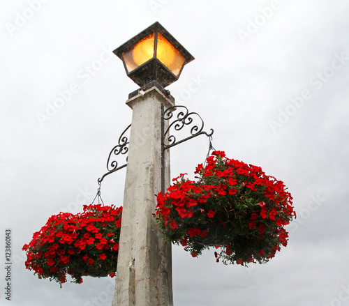 Street light lamp post with baskets of red flowers