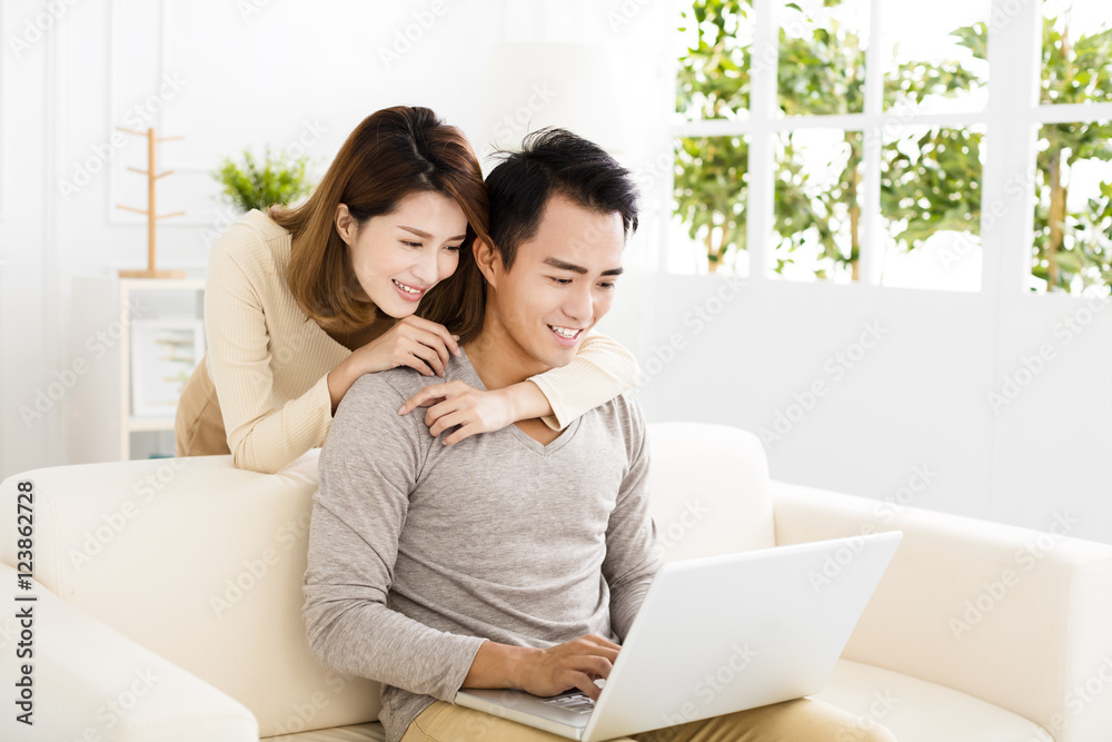 happy young couple using laptop on sofa happy young couple using laptop on sofa