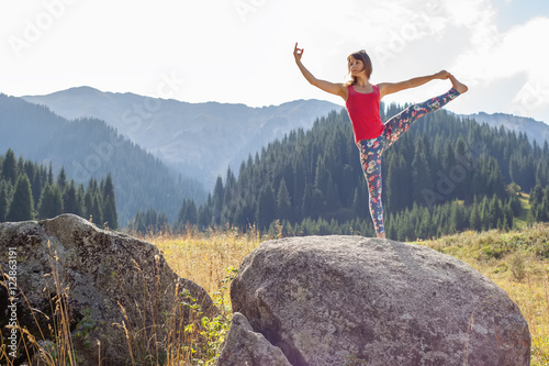 young woman doing yoga on a rock