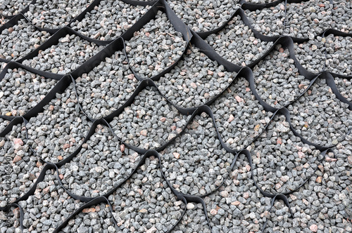 The design of the slope. Plastic black honeycomb frame filled with small natural stones closeup. photo