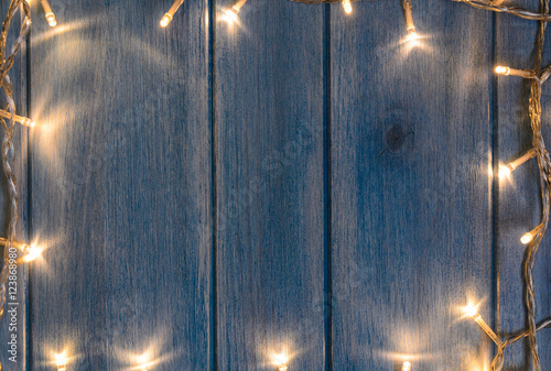 Christmas lights on blue wooden table, view from above