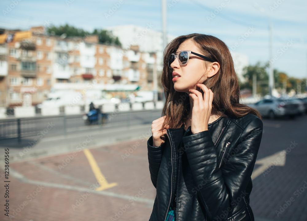 Urban fashionable girl posing in a leather jacket outdoors in the city