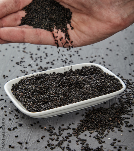 Black sesame seeds sprinkling from hand