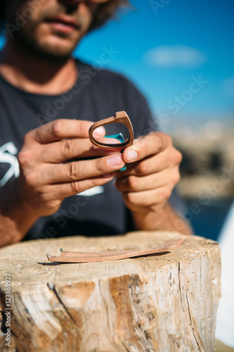 Unrecognizable man treats wooden rim glasses