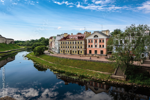View of the embankment from the bridge through the river of Pskov in summer sunny day