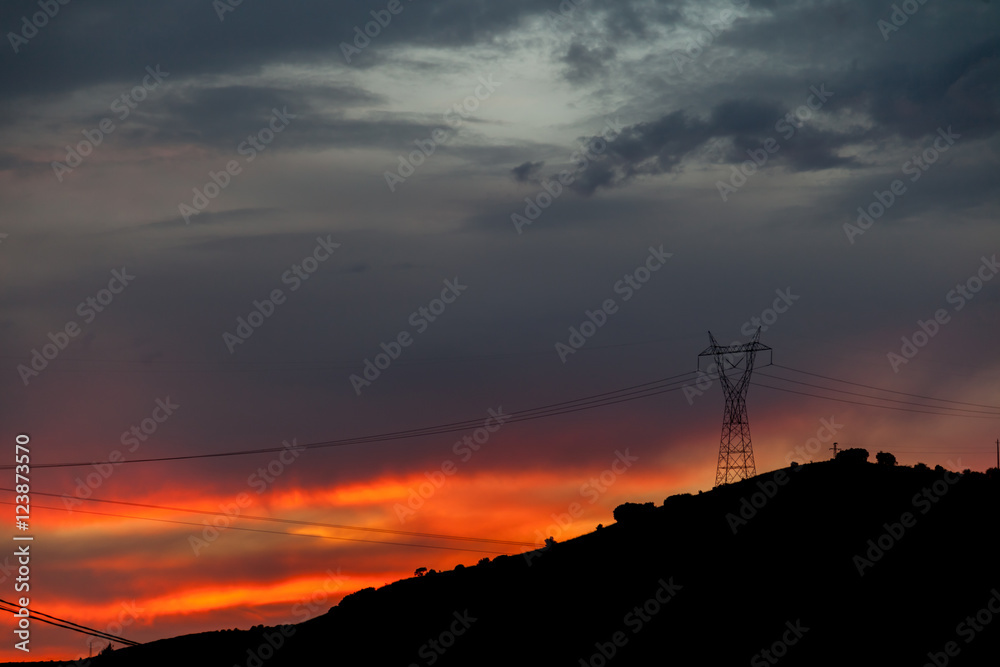 Anochecer rojo/ Anochecer con cielos rojos y azules sobre montañas y torres de alta tensión. Anochecer rojo/ Anochecer con cielos rojos y azules sobre montañas y torres de alta tensión.