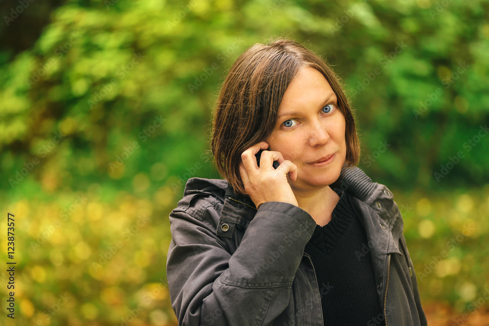 Beautiful woman talking on mobile phone in autumn park Beautiful woman talking on mobile phone in autumn park