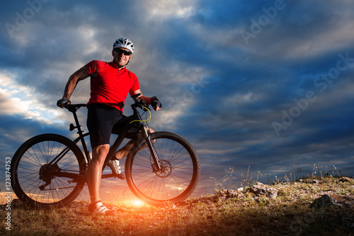 Cyclist riding mountain bike on trail at evening.