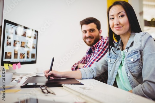 Smiling business people with graphic tablet at desk