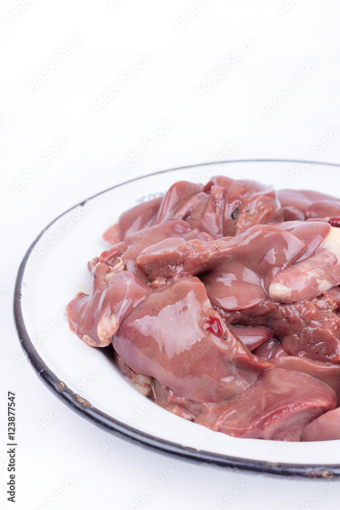 Raw chicken liver in the metal plate over white background