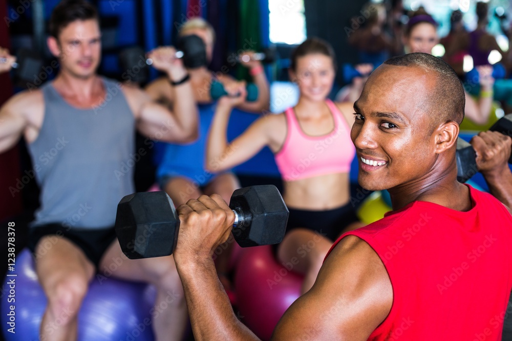 Portrait of smiling man holding dumbbell in gym