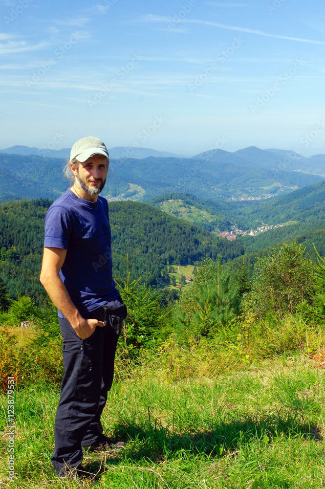 Bearded man, hiker, standing in the mountains and looks into the distance. Back view. Sunny day. Bearded man, hiker, standing in the mountains and looks into the distance. Back view. Sunny day.