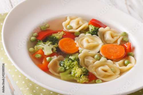 Italian soup with tortellini and vegetables closeup at the plate. horizontal 