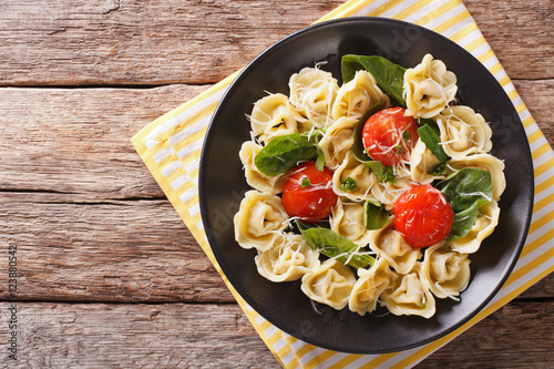 Freshly cooked tortellini with spinach and parmesan on a plate. horizontal top view
