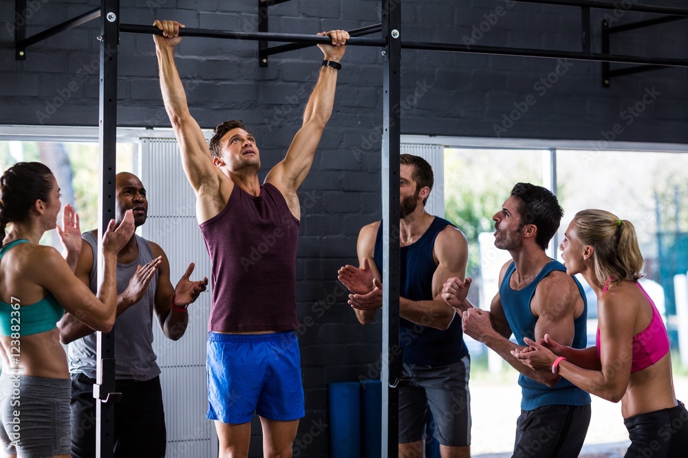 Fotografie Friends cheering man doing chin-ups