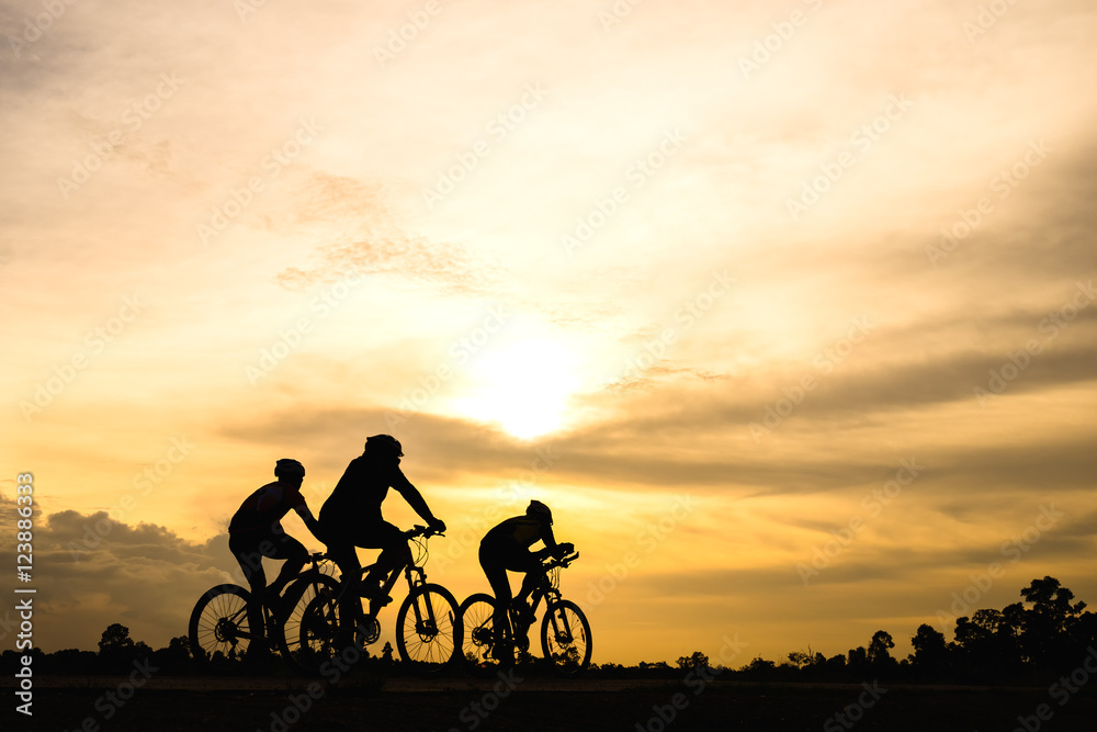 Obraz premium Silhouette of cyclist with friend motion on sunset background