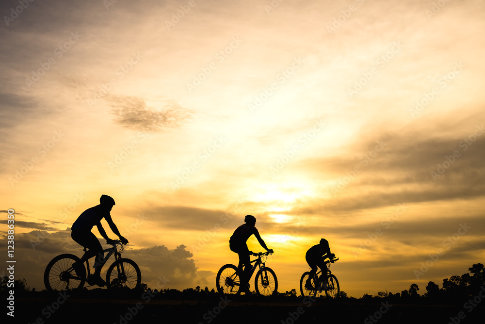 Obraz premium Silhouette of cyclist with friend motion on sunset background