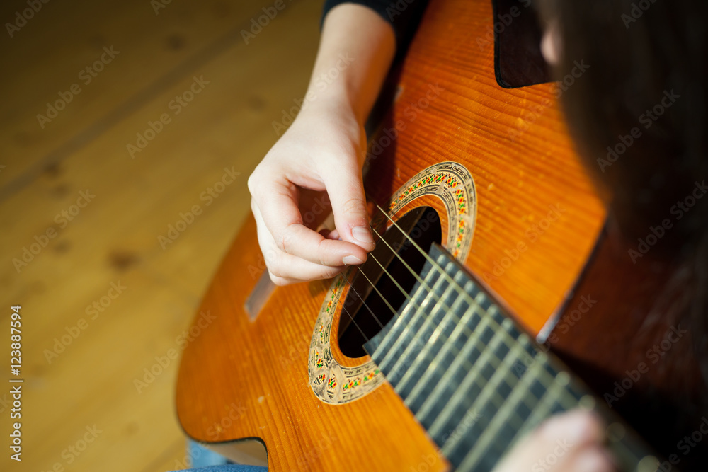Fototapeta premium Young woman playing on the old wood guitar and enjoying nice tim