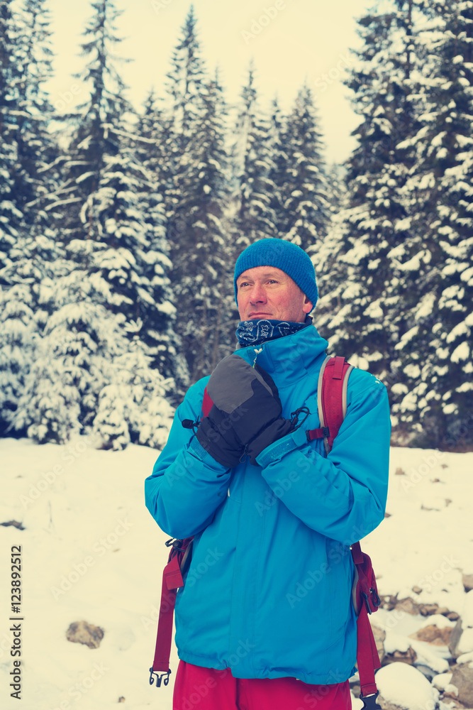 Hiker, man warms his hands in mittens