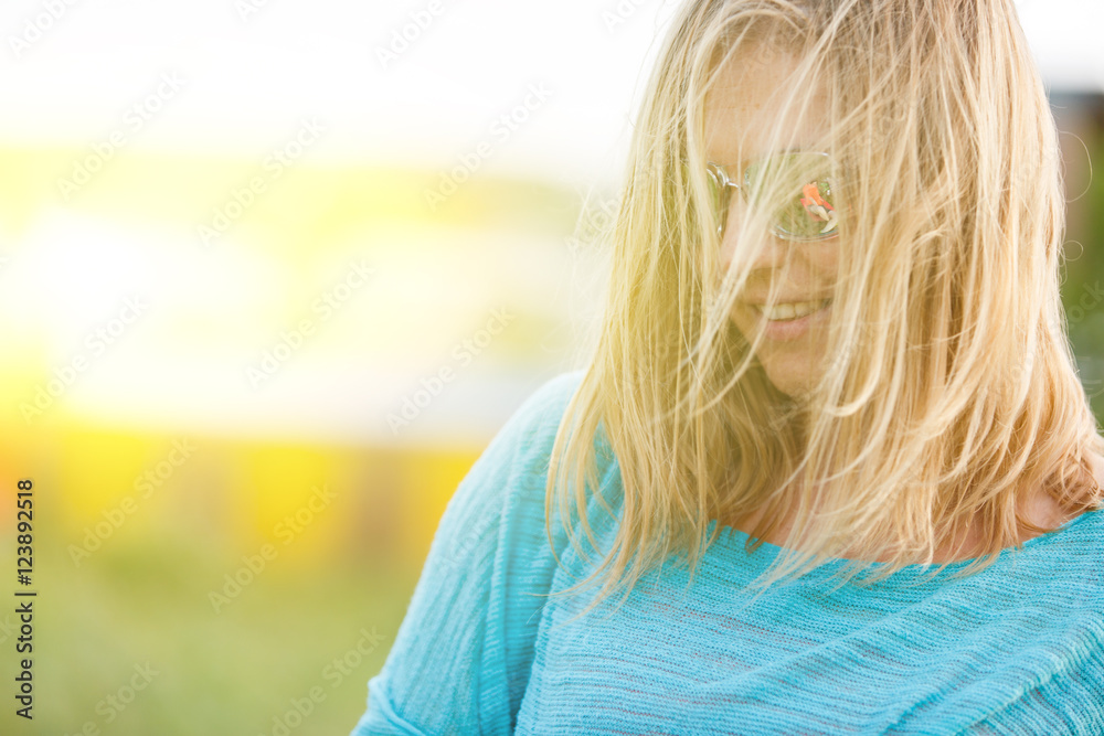 Smiling beautiful blonde woman with sunglasses in summer windy day