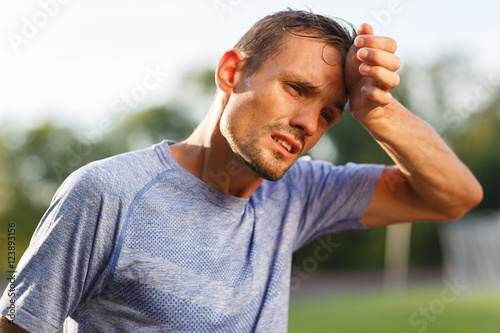 Tired exercise and heat sporty man wiping sweat from face