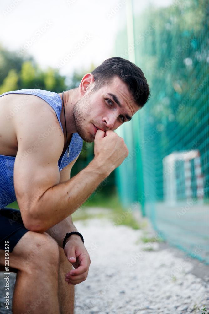 Obraz premium Athletic caucasian man sitting on bench and looking at camera