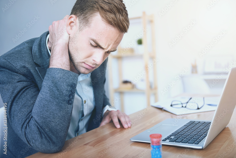 Exhausted young man suffering from pain in the neck Exhausted young man suffering from pain in the neck