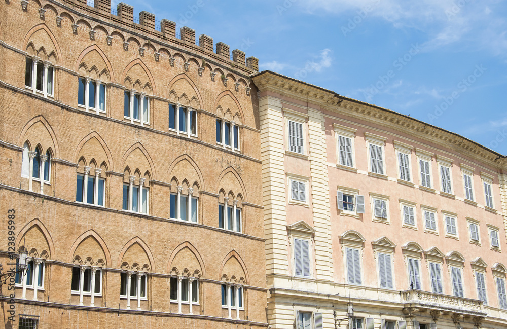 Facade of a historic buildings with its windows on the square of Siena, Italy.