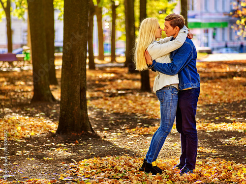 Happy couple kissing in autumn park . Loving couple kissing in sun in autumn park. Love of youth and beauty concept.
