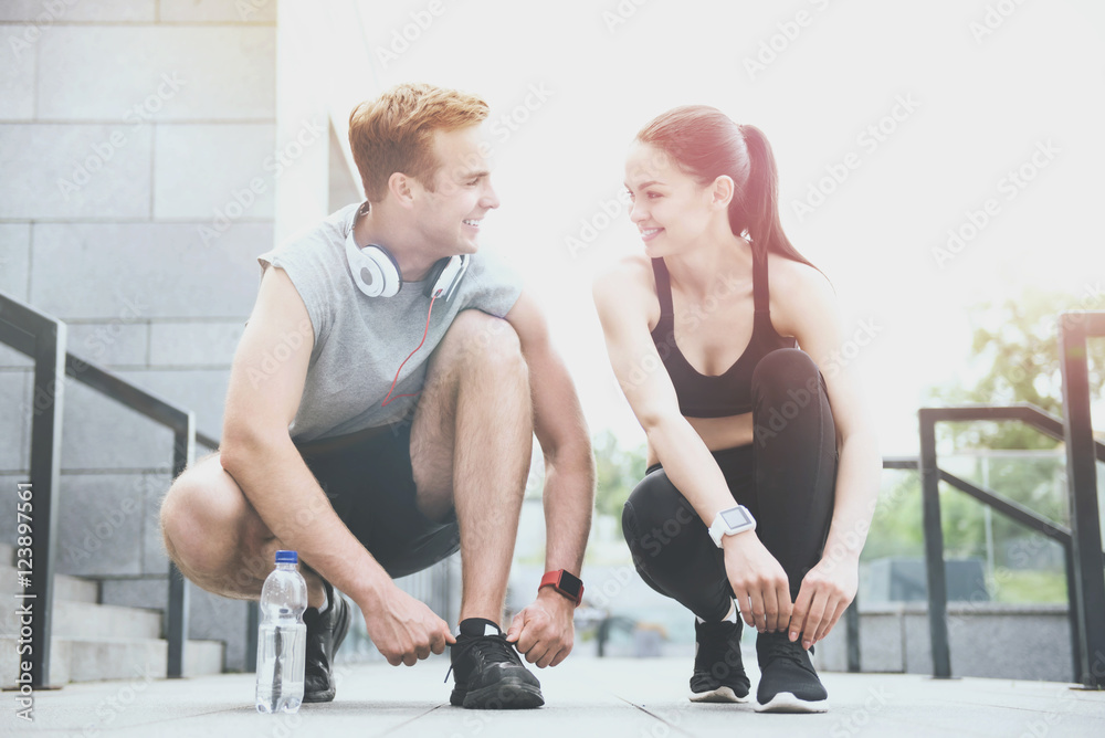 Obraz premium Delighted friends tying shoelaces before common training.