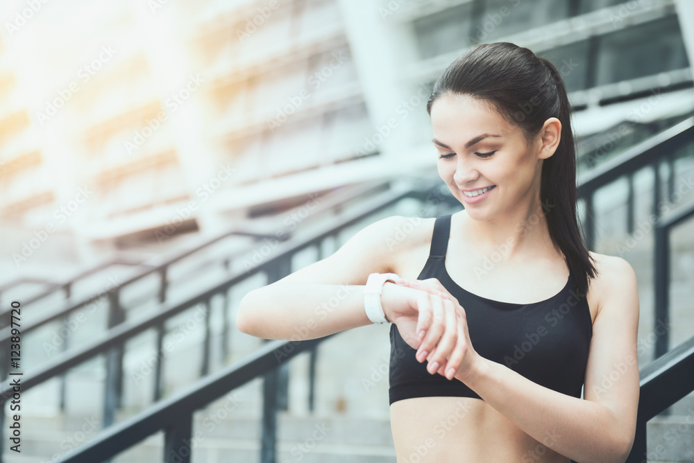 Smiling girl using a smart watch near the stadium Smiling girl using a smart watch near the stadium