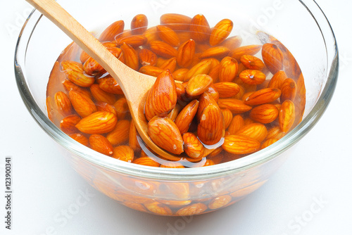 Raw almonds soaking in a white bowl of water