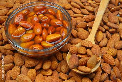Raw almonds soaking in a white bowl of water