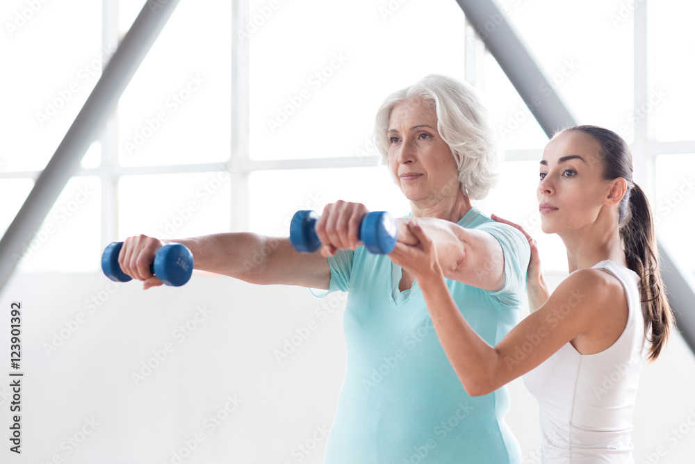 Determined persistent woman holding dumbbells in front of her