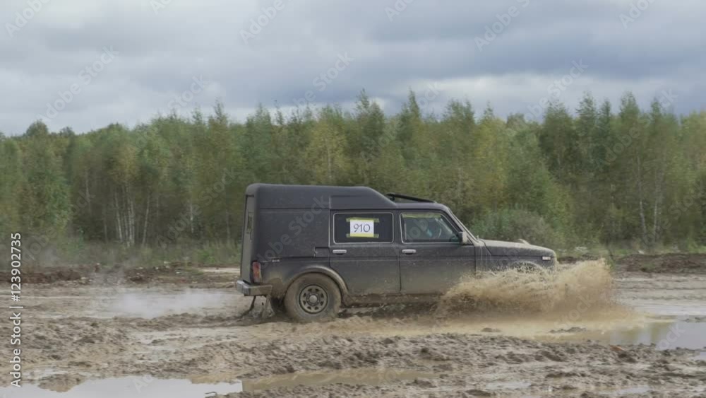 Jeep rides on a dirt road. The car enters the puddle of mud Jeep rides on a dirt road. The car enters the puddle of mud