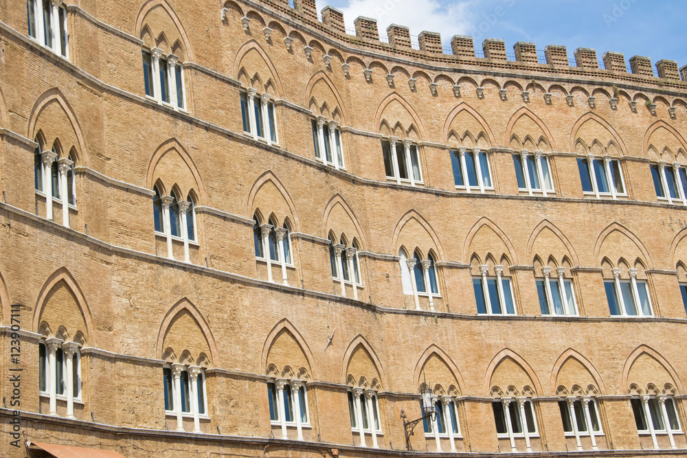 Facade of a historic building with its windows on the square of Siena, Italy.