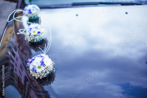 Little blue bouquets lie on the black car's hood