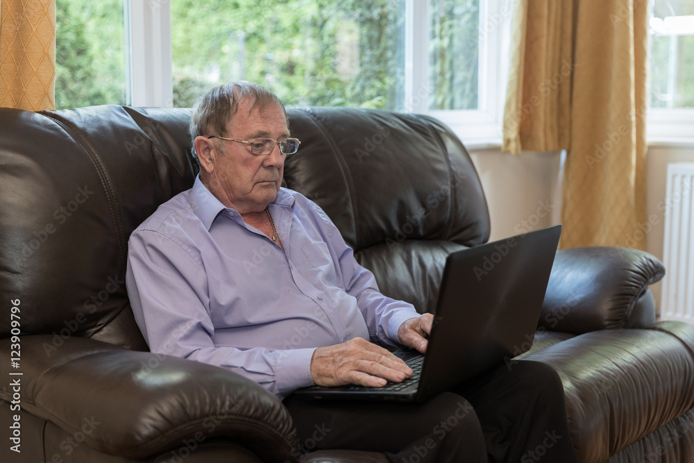 Old aged pensioner, man sat on sofa using a laptop Old aged pensioner, man sat on sofa using a laptop