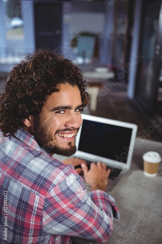 Portrait of man smiling while using laptop
