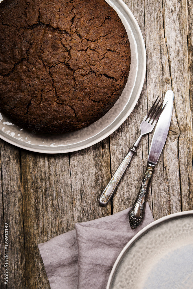 Fototapeta premium Healthy chocolate cake with beet on a gray plate with the effect of craquelure on the old wooden background. Selective focus