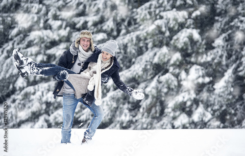 Man carrying girlfriend in winter landscape