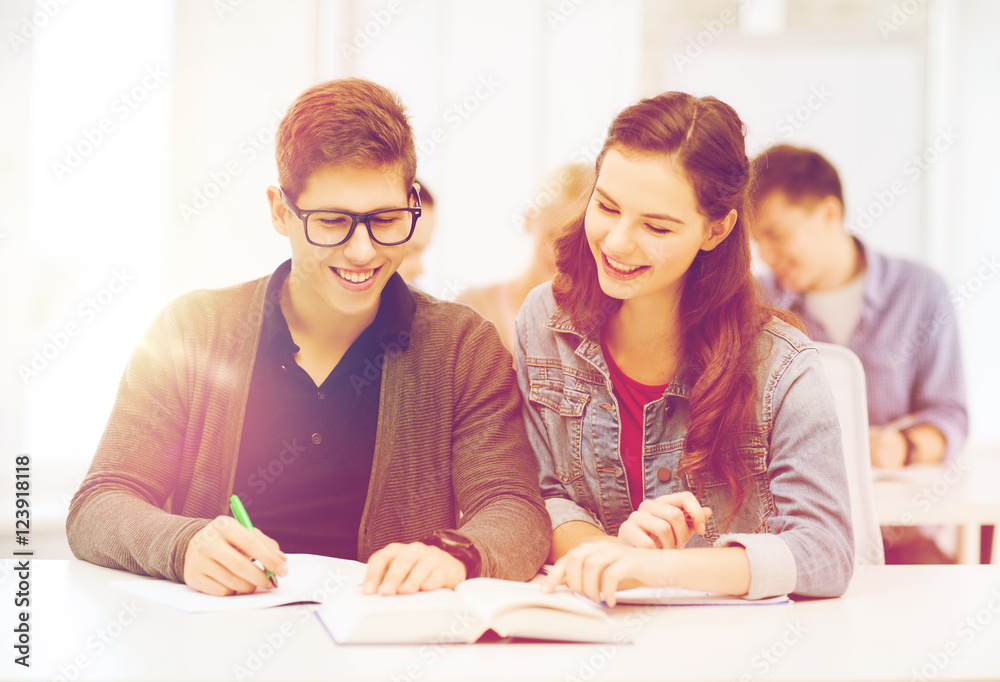 two teenagers with notebooks and book at school two teenagers with notebooks and book at school