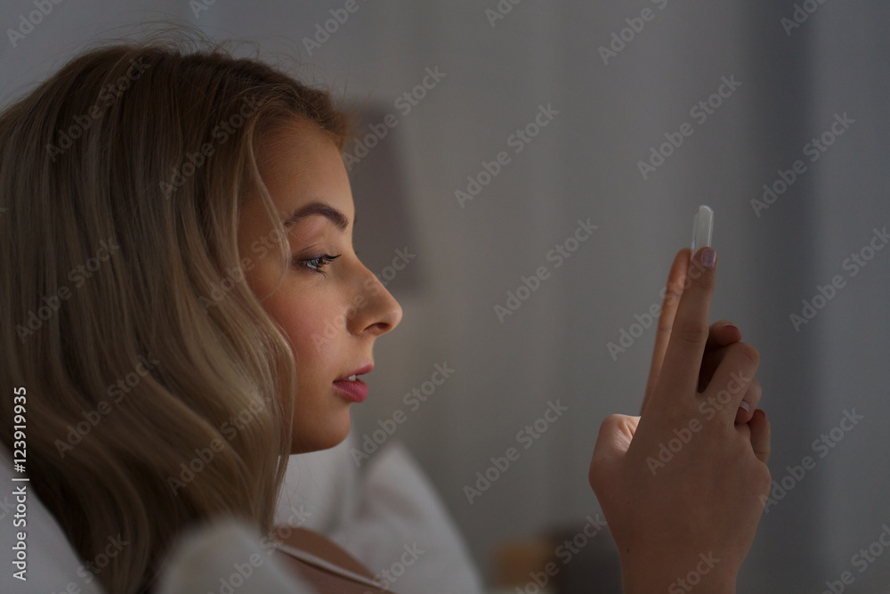 young woman with smartphone in bed at night young woman with smartphone in bed at night