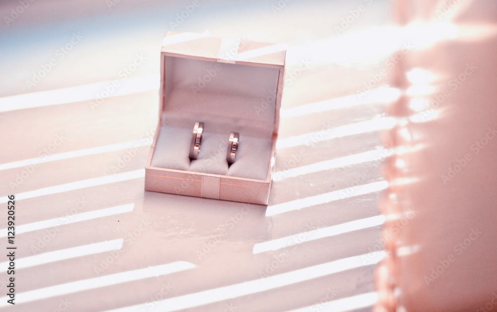 Golden wedding rings put in a pink box stand on the windowsill Golden wedding rings put in a pink box stand on the windowsill