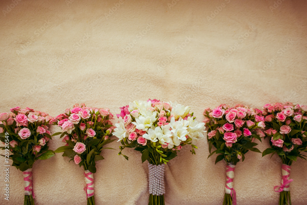 Pink wedding bouquets lie on the beige bed