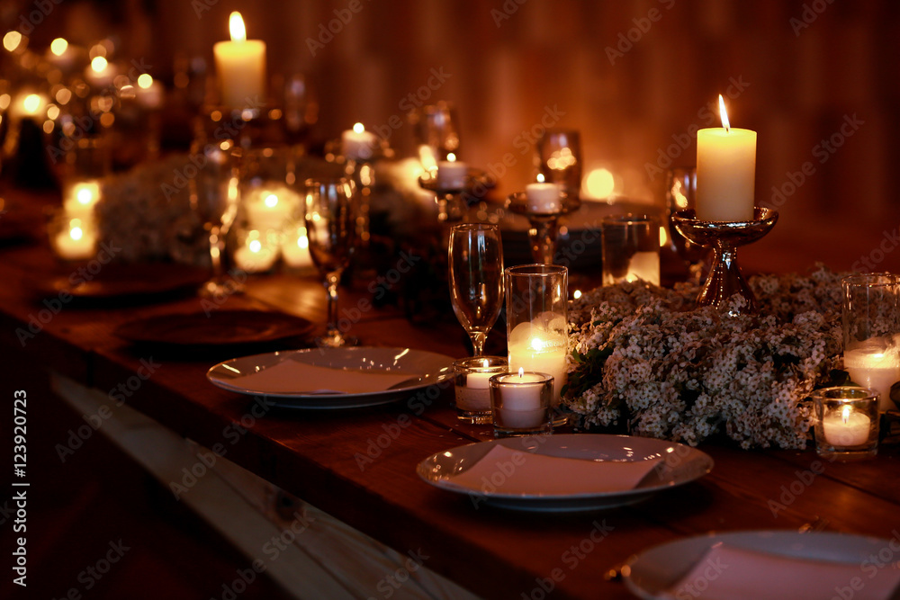 White candles burn over white dinner plates on the dinner table